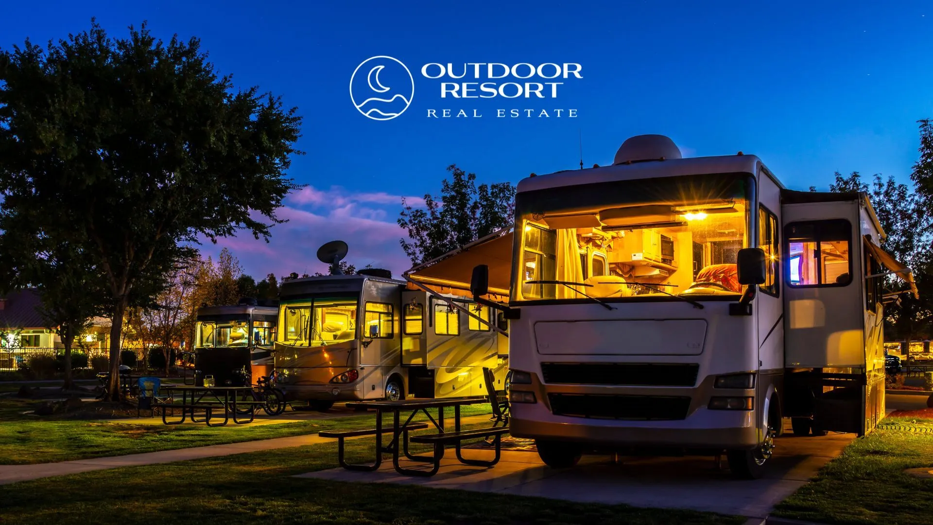 White RV viewed through a front window at dusk, with interior lights on and other RVs parked behind it.