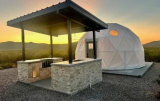 Covered outdoor kitchen beside a glamping dome at sunset, Glamp the World property in Clint, Texas