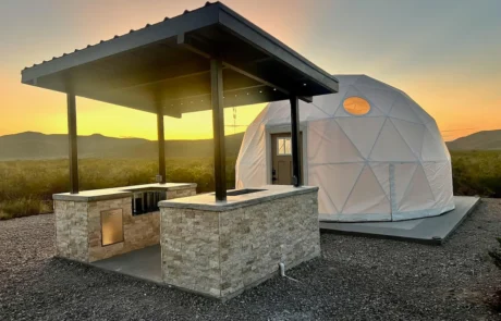 Covered outdoor kitchen beside a glamping dome at sunset, Glamp the World property in Clint, Texas