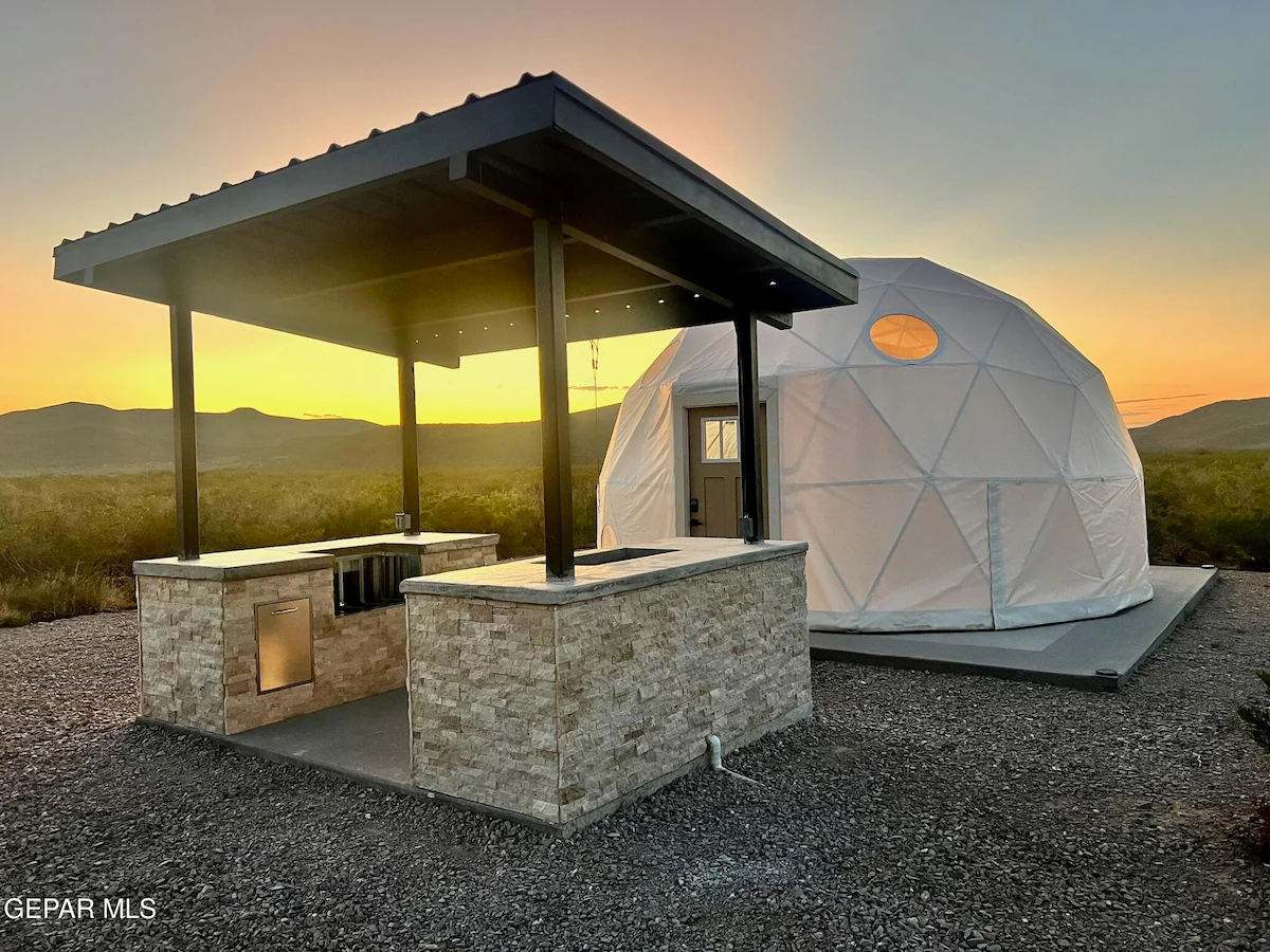 Covered outdoor kitchen beside a glamping dome at sunset, Glamp the World property in Clint, Texas