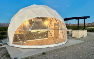 Luxury glamping dome lit up at dusk with covered patio, Glamp the World in Clint, TX
